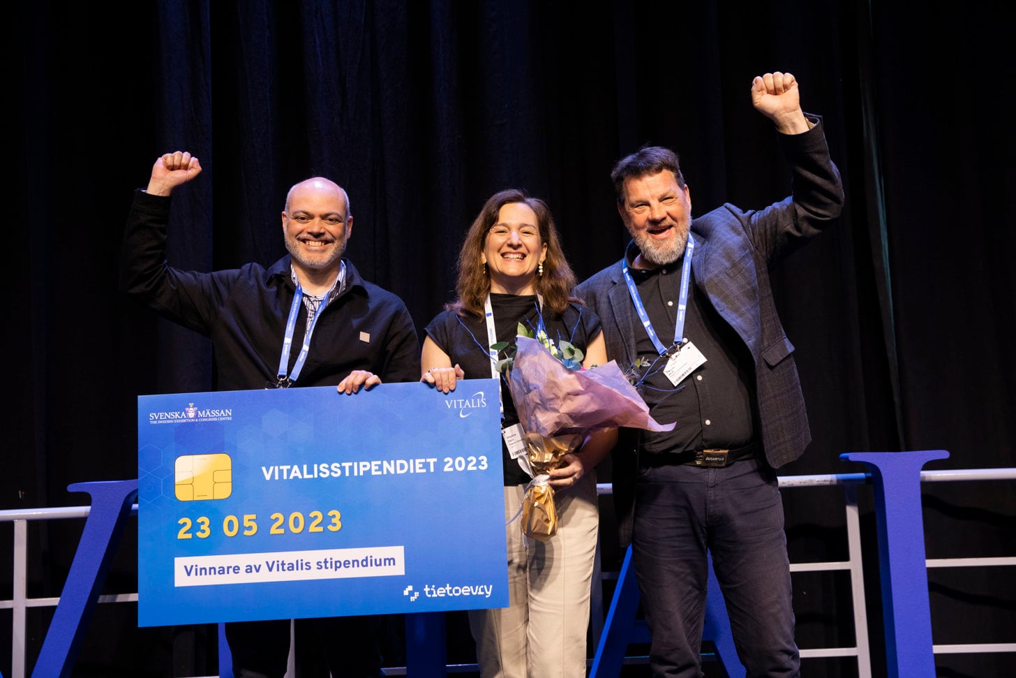 Three people on stage celebrating a Vitalisstipendiet win