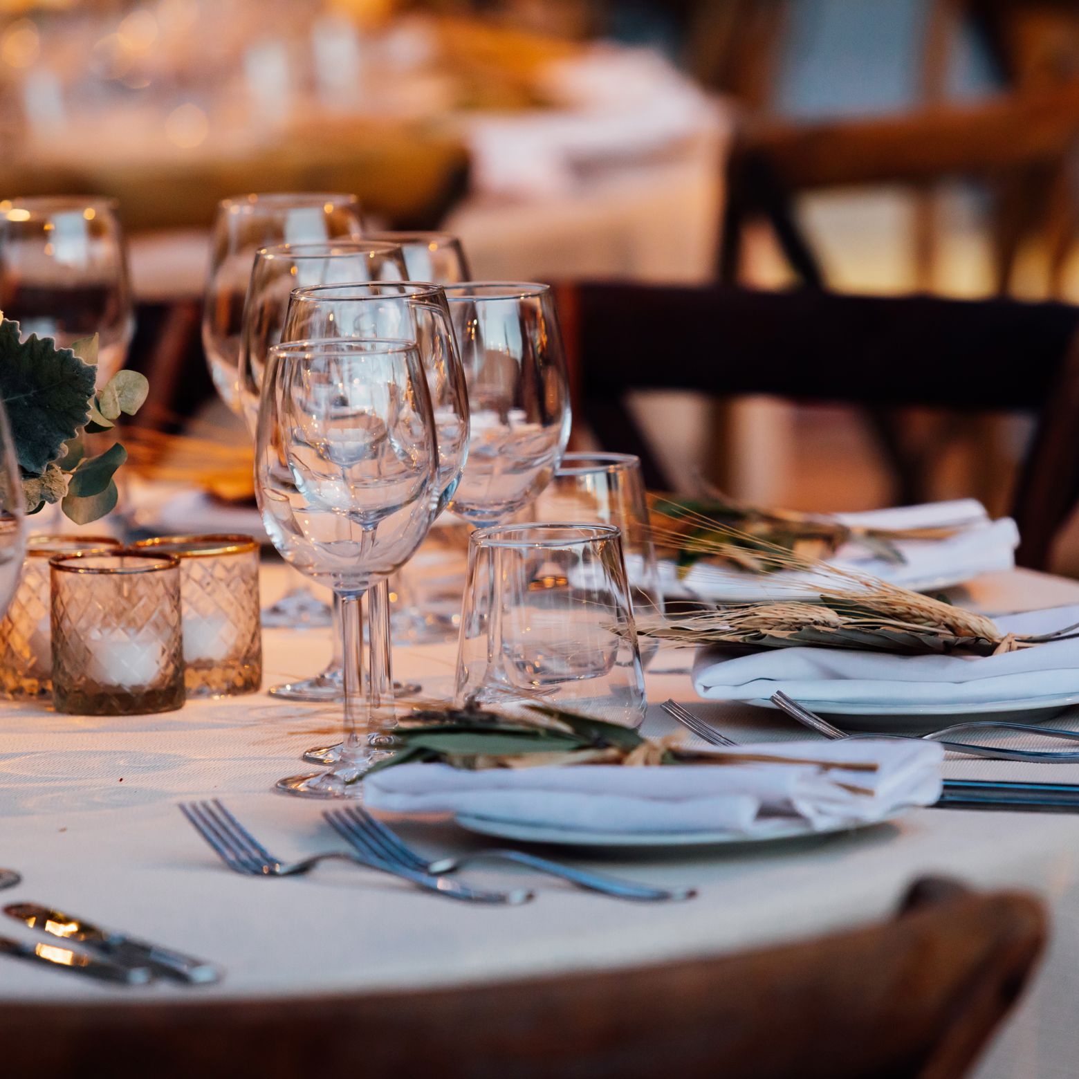 Elegant dinner table setting prepared for an exclusive networking event with floral decorations, wine glasses, and fine dining details.